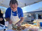 Andy Gordon from Caterina puts together the American-style cheeseburgers that won the first annual burger battle, part of the Autumn Celebration of Food. Picture by Glenn Ellard.