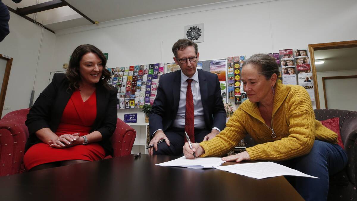 Illawarra Women's Health Centre executive director Sally Stevenson signs the grant agreement with Cunningham MP Alison Byrnes and Whitlam MP Stephen Jones. Picture by Robert Peet.